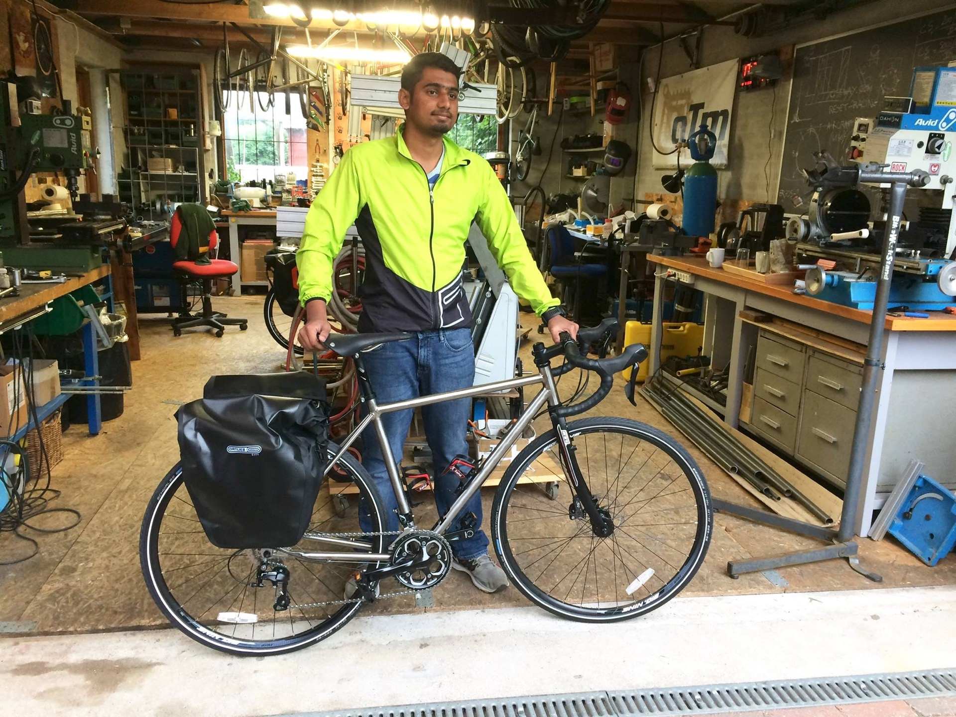 Adhith standing with his hand-built titanium touring bike in a workshop