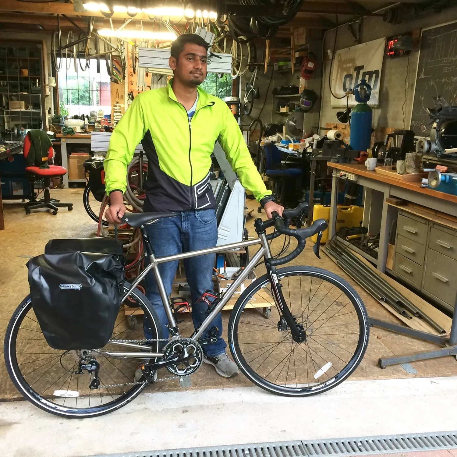Adhith standing with his touring bike in a workshop