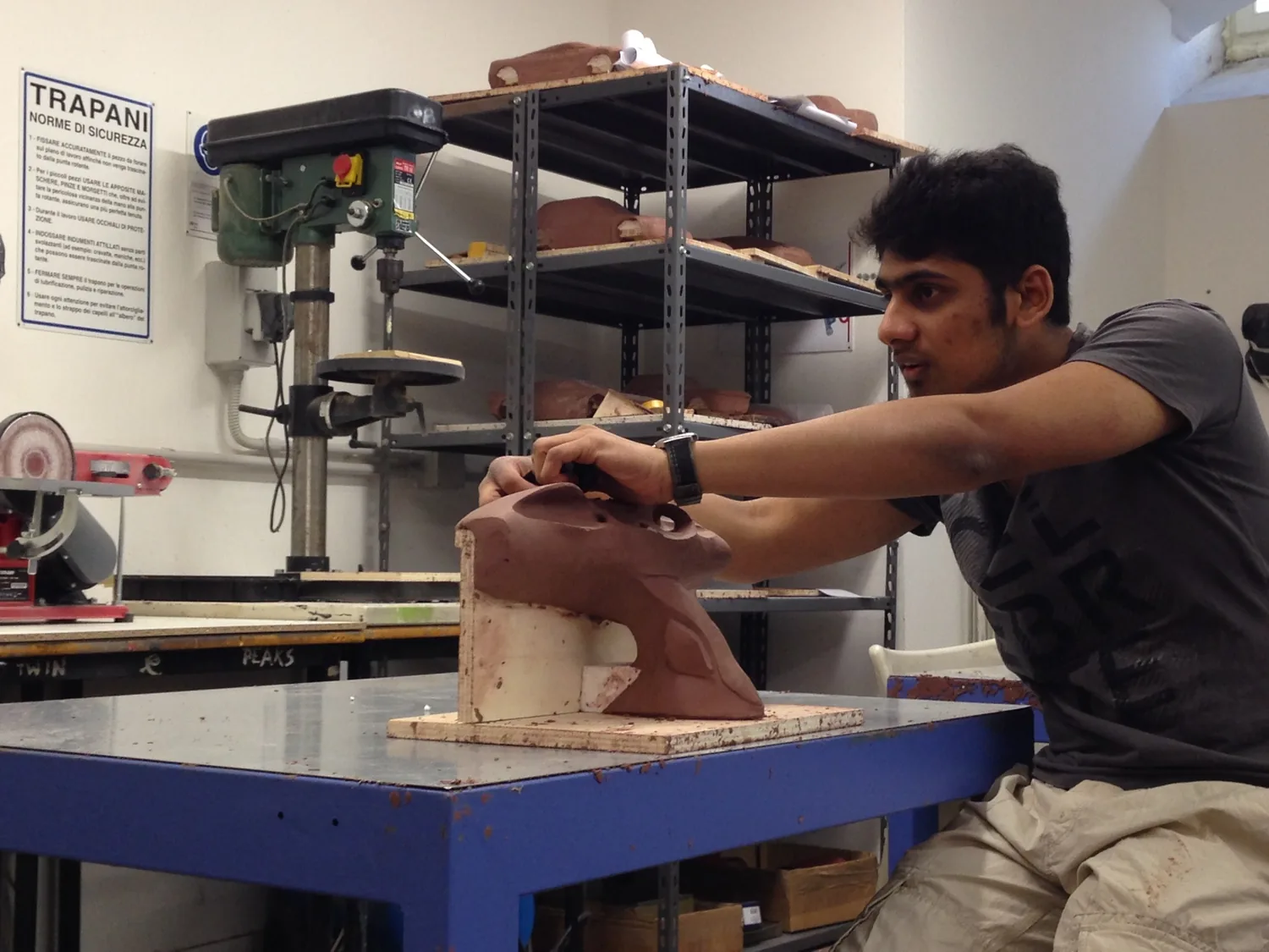 Adhith shaping a clay model at a workshop bench