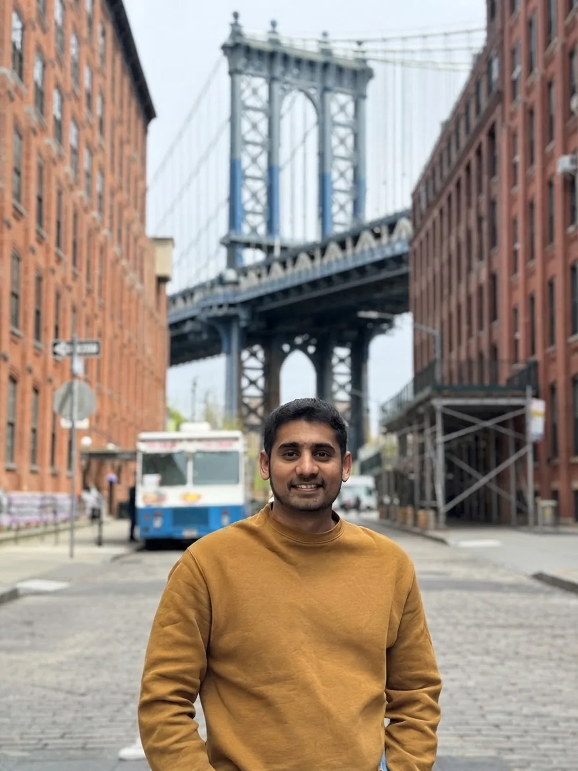 Adhith on a Brooklyn street with the Manhattan Bridge behind him